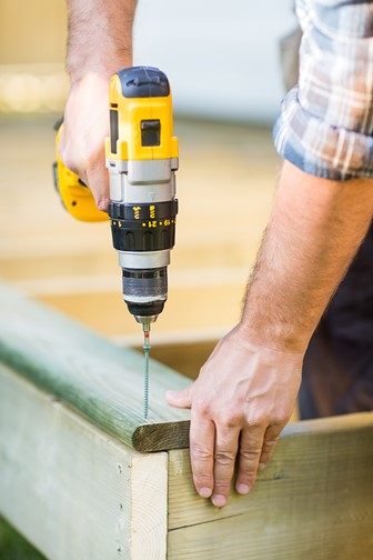 carpenter using a cordless drill to drill a hole